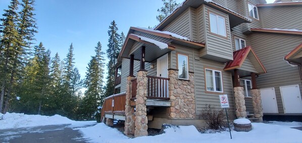 Une maison à plusieurs étages, avec des fondations en pierre, un balcon et un panneau indiquant « Stationnement interdit ».