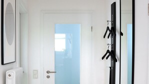 A hallway with a white door, a radiator, and two black mirrors on the wall.