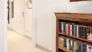A hallway with a wooden bookshelf, a wall-mounted bull's head, and a framed sign.