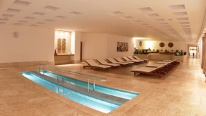 En hotellobby med swimmingpool, liggestole og en reception.