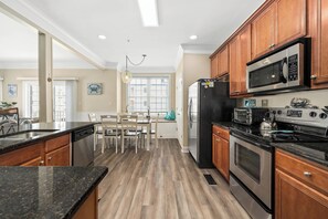 Una cocina con gabinetes de madera, electrodomésticos de acero inoxidable y una zona de comedor con sillas y una mesa.