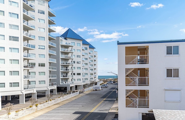 Un hotel de varios pisos con balcones, estacionamiento y vistas a la playa.