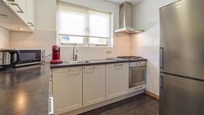 Una cucina moderna con frigorifero in acciaio inossidabile, piano cottura a gas, forno a microonde e una moka rossa.
