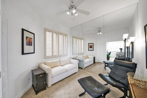 A spacious living room with a white sofa, a black leather chair, and a small table with a basket. - Waterfront 1st Floor, Gated, 2 Bd,2Ba + Den, Family Friendly, Pet Friendly. (Scottsdale)