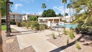 A pool area with a fence, palm trees, and a building with a pool in the background. - Waterfront 1st Floor, Gated, 2 Bd,2Ba + Den, Family Friendly, Pet Friendly. (Scottsdale)