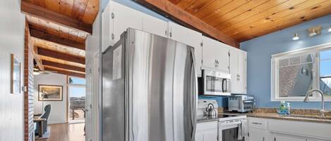 Una cocina moderna con electrodomésticos de acero inoxidable, encimera de granito y vistas a la ciudad.