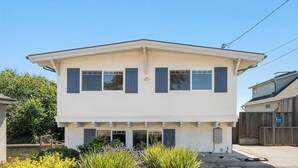 A two-story building with a flat roof, multiple windows, and a gated entrance. - Bay Watch Beach House (Santa Cruz)