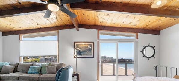 A room with a wooden ceiling, a large window, a framed picture, and a ship's wheel on the wall. - Bay Watch Beach House (Santa Cruz)