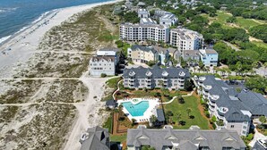 An aerial view of a coastal resort with multiple buildings, a beach, and a swimming pool.