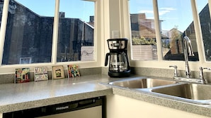 Una cocina con ventanas amplias, cafetera y lavavajillas.