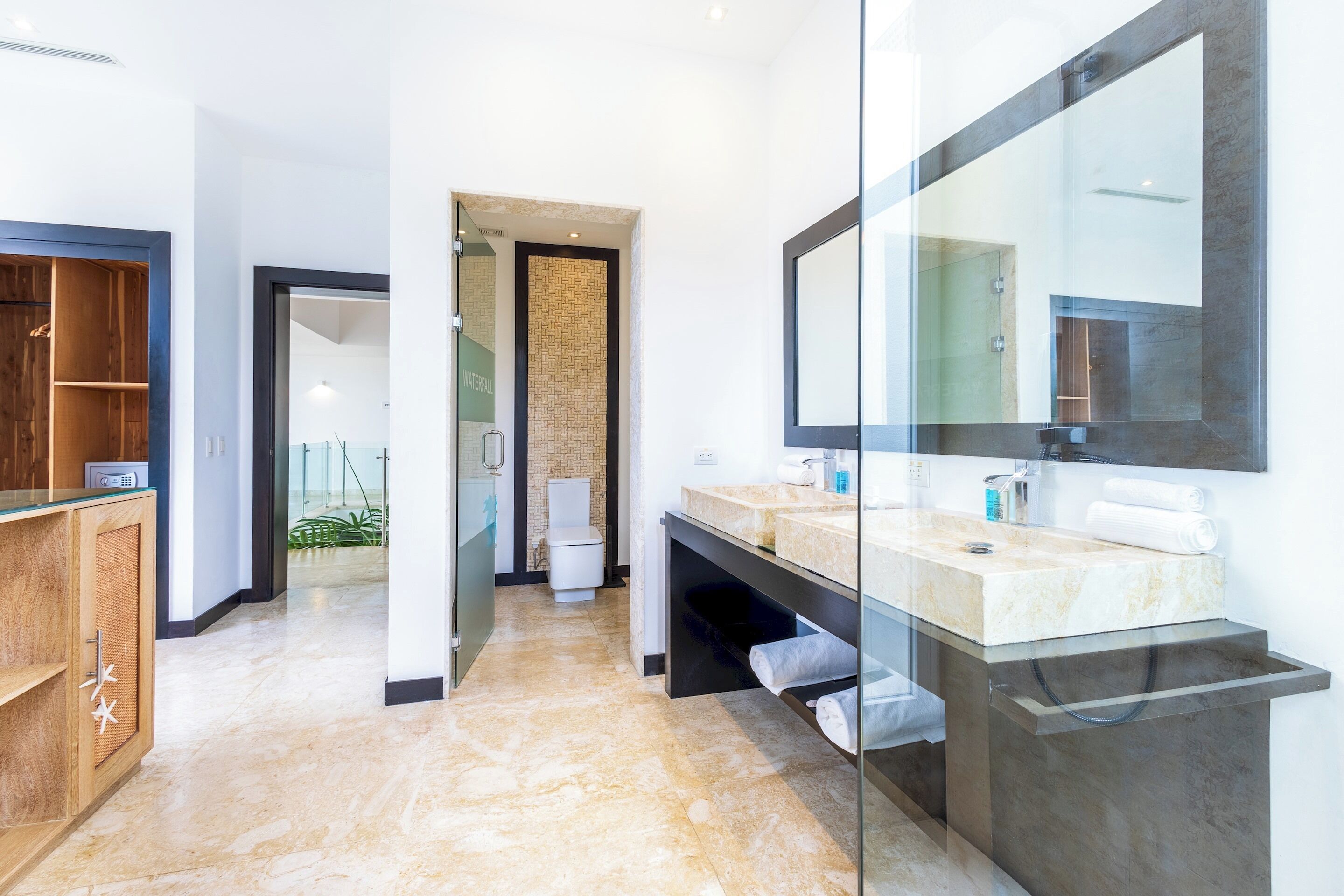 A modern bathroom with a glass shower enclosure, a large mirror, and a marble countertop.