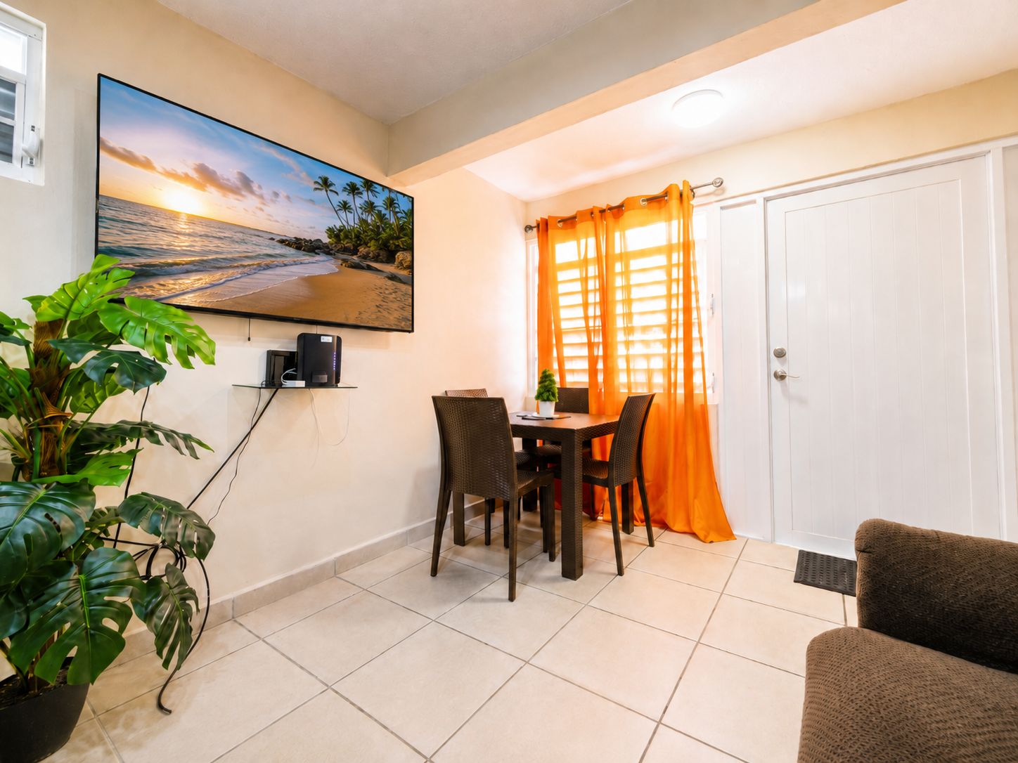 Ein Essbereich mit Tisch und Stühlen, einem an der Wand befestigten Fernseher und einer Zimmerpflanze.
