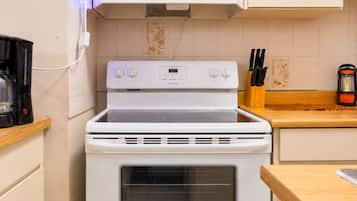 Una cocina con estufa, horno y cafetera sobre la encimera.