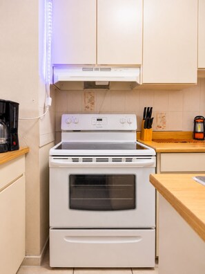 A kitchen with a white stove, oven, and a coffee maker on the counter. - Jobos Beach Apartment A-3 (Isabela)