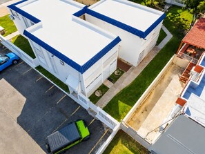 A multi-story building with a flat roof and white walls, surrounded by a parking area and a small garden. - Jobos Beach Apartment A-3 (Isabela)