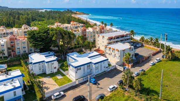 A coastal hotel with multiple buildings, a parking area, and a view of the ocean. - Jobos Beach Apartment A-3 (Isabela)
