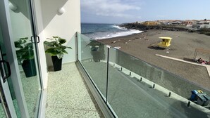Un balcon avec vue sur une plage, un poste de surveillance des sauveteurs et un ciel dégagé.