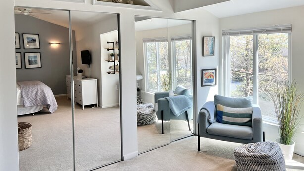 A modern bedroom with a bed, bedside table, and a large mirror. - UPDATED IN 2022  @Oceanfront - 3 Blocks 2Beach! 2 Suites 2.5 bath - great deck! (Virginia Beach)