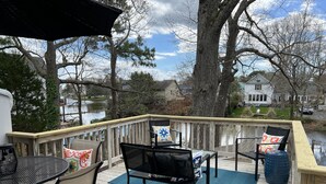 A wooden deck with outdoor furniture, including chairs and a table, overlooking a body of water and houses. - UPDATED IN 2022  @Oceanfront - 3 Blocks 2Beach! 2 Suites 2.5 bath - great deck! (Virginia Beach)