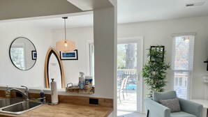 A modern kitchen with a wooden countertop, a sink, and a mirror. There is a hanging light fixture and a window with a view of the outdoors. - UPDATED IN 2022  @Oceanfront - 3 Blocks 2Beach! 2 Suites 2.5 bath - great deck! (Virginia Beach)