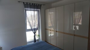 Une chambre à coucher avec un lit, une fenêtre avec des rideaux légers et une armoire avec des portes coulissantes.