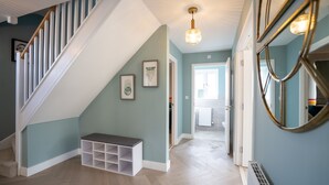 A staircase with white railings, a bench, and a wall-mounted mirror. - 6 Bedroom New Build Detached House in Bicester (Bicester)