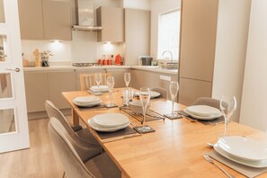 A modern dining area with a wooden table set for six, equipped with plates, glasses, and cutlery. - Stylish Chilterns Hills Escape | Walks & Parking (High Wycombe)