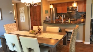 A modern dining area with a wooden table, white chairs, and a chandelier.