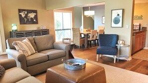 A living room with a sofa, ottoman, and a dining area with chairs and a table.