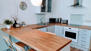 A modern kitchen with a wooden countertop, stainless steel appliances, and a built-in oven. - Great value in Prenzlauer Berg, free parking (Berlin)