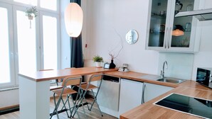 A modern kitchen with a wooden countertop, white cabinets, and a built-in dishwasher. - Great value in Prenzlauer Berg, free parking (Berlin)