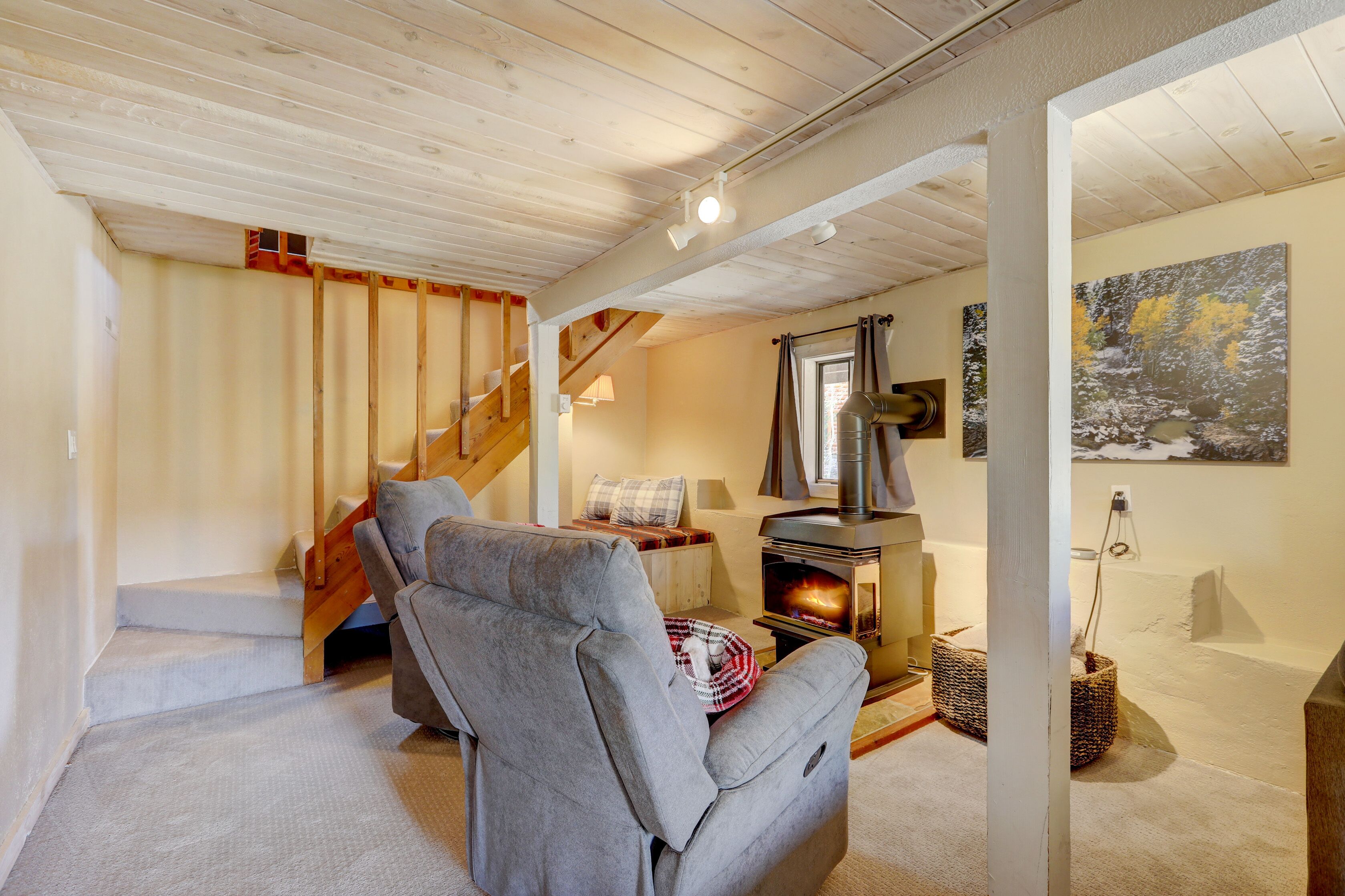 Ein gemütliches Wohnzimmer mit Kamin, einer Couch und einer Treppe, die in einen oberen Bereich führt.