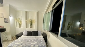 A bedroom with a large bed, a window, and a view of the city at night. - On the beach with unbeatable views  (Telde)