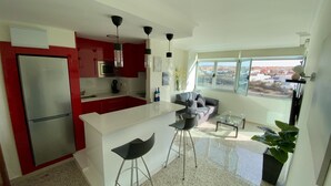 A modern kitchen with red cabinets, a white island, and a large window offering a city view. - On the beach with unbeatable views  (Telde)