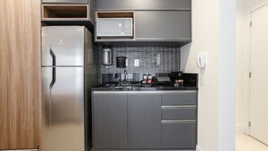 Una cocina moderna con un refrigerador de acero inoxidable, un microondas y una cafetera.