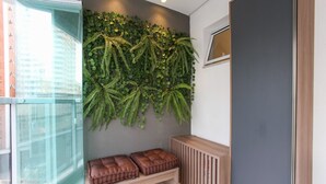 Un interior moderno con una puerta de cristal, un banco con cojines, una planta en la pared y un radiador.