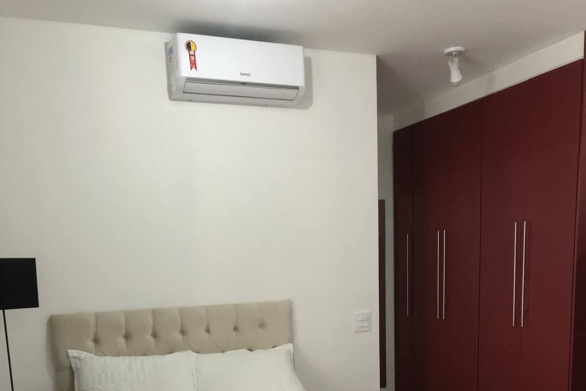 Un dormitorio con cama, armario y aire acondicionado.