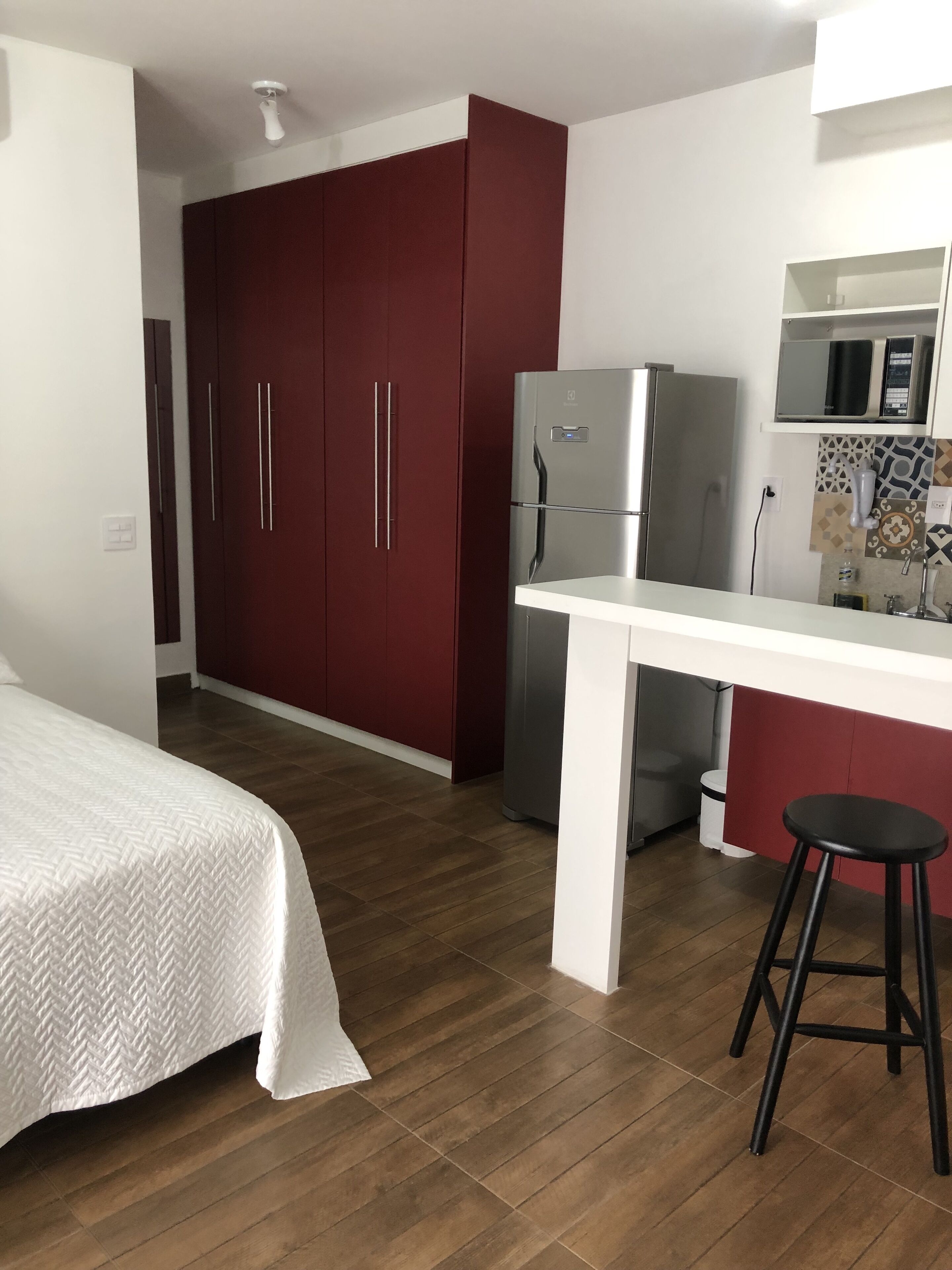 A compact kitchen with a refrigerator, microwave, and a small bar area.