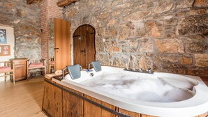 A bathroom with a stone wall, wooden bathtub, and a wooden bench. - Cozy home in Veprinac (Veprinac)