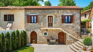 A stone building with a tiled roof, two wooden doors, and a balcony with a metal railing. - Cozy home in Veprinac (Veprinac)