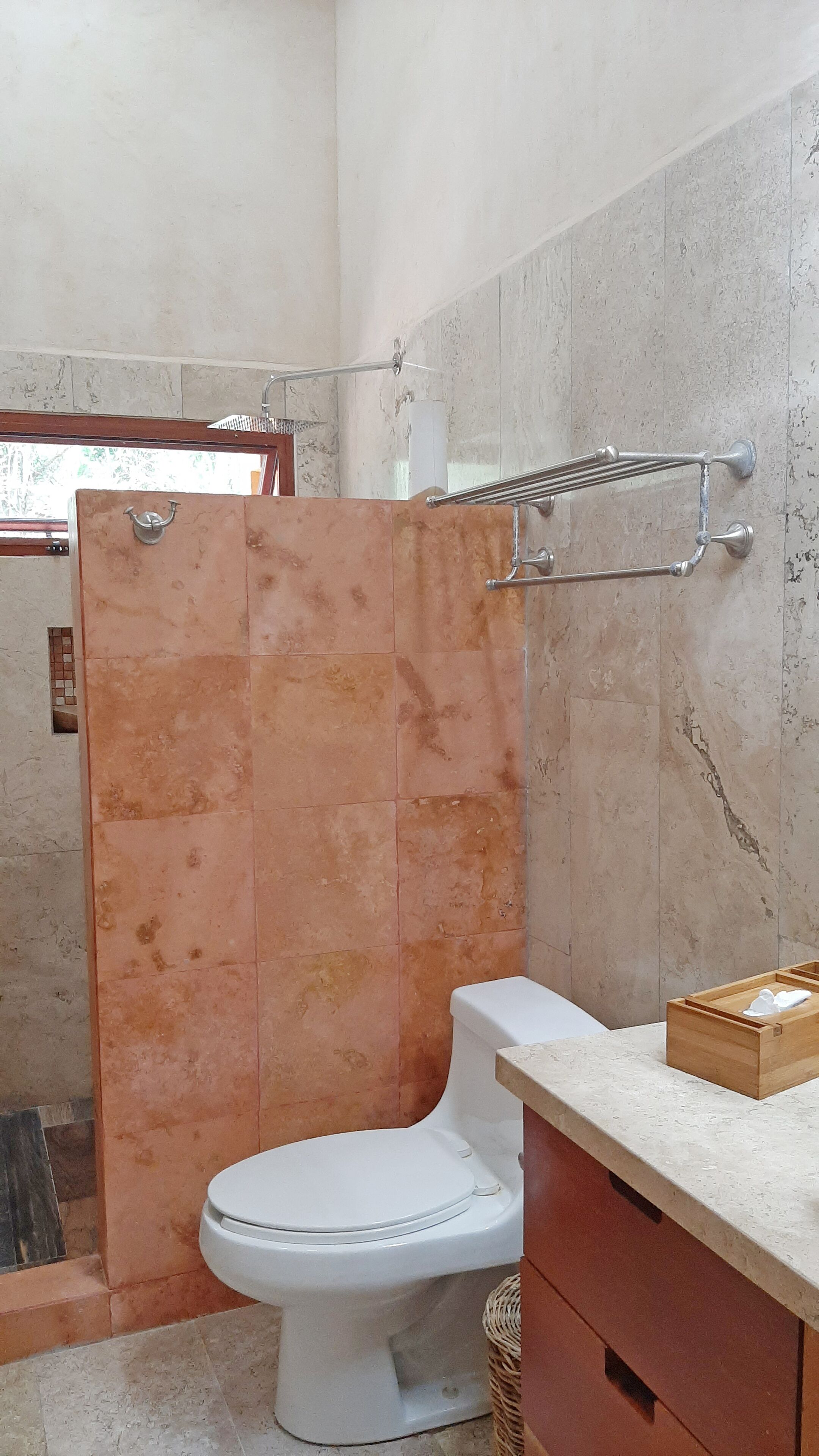 Une salle de bain avec des toilettes blanches, un espace douche et un meuble-lavabo en bois avec un évier.