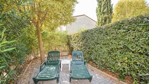 Un jardín con dos sillones verdes y una mesita.
