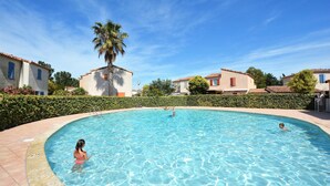 Una piscina rodeada de casas, bajo un cielo azul y despejado.