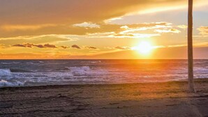 Un atardecer sobre el océano con olas rompiendo en la orilla.