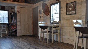 Un espace repas avec des murs en bois, un plancher en bois et une table entourée de chaises. Il y a une porte et une fenêtre donnant sur un paysage agréable.