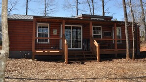 Une cabane en bois dotée d’une véranda, de grandes fenêtres et d’un toit en métal.