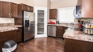 A modern kitchen with dark wooden cabinets, stainless steel appliances, granite countertops, and a built-in dishwasher. - 3 Beds 2 Baths by Costco, GP Airport, Restaurants (Grande Prairie)