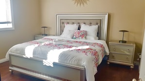 A neatly made bed with floral bedding, a tufted headboard, and two bedside tables with lamps. - 3 Beds 2 Baths by Costco, GP Airport, Restaurants (Grande Prairie)