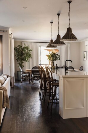 Een moderne keuken met een centraal eiland, donker houten vloeren en hanglampen.