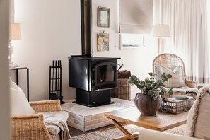 A cozy living room with a fireplace, wicker furniture, and a potted plant.